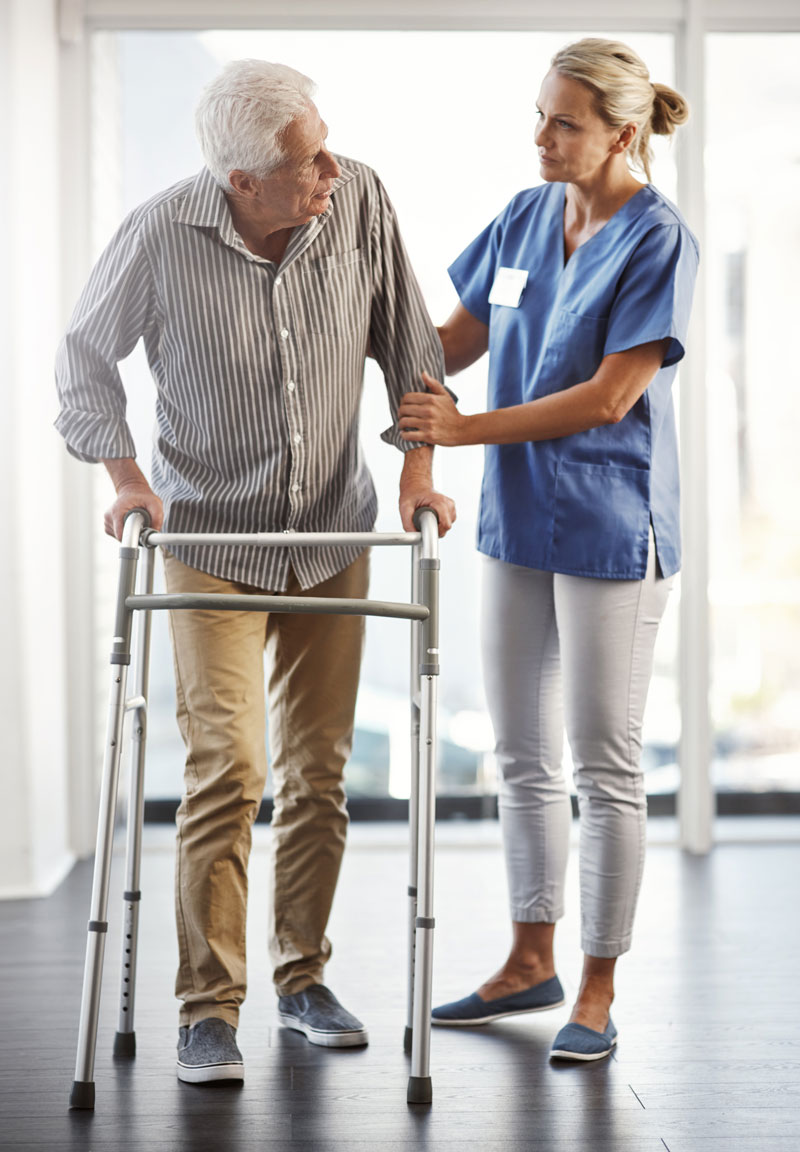 older adult male using a walker with help from a woman